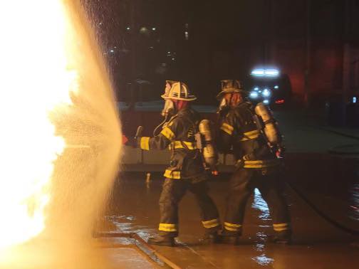 Two Firefighters with a hose fighting a fire